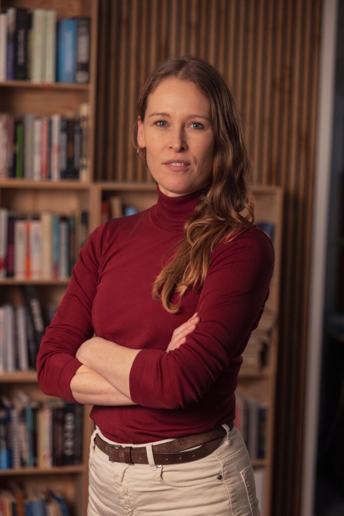Lea Korsgaard, co-founder and Editor-in-Chief of Zetland, standing in front of a bookshelf